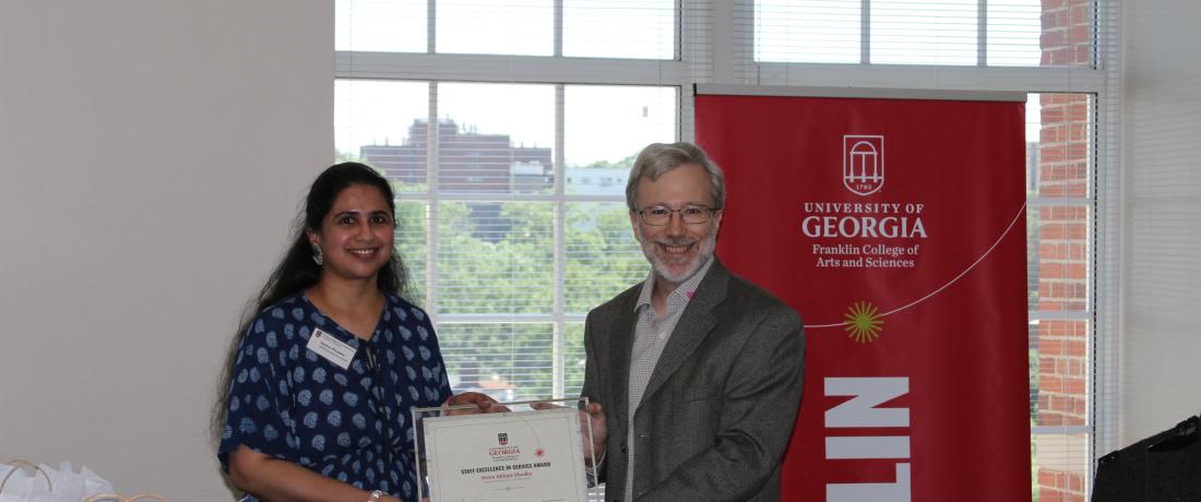 Dr. Craig Wiegert presenting the 2025 Staff Excellence Award to Netra Phadke
